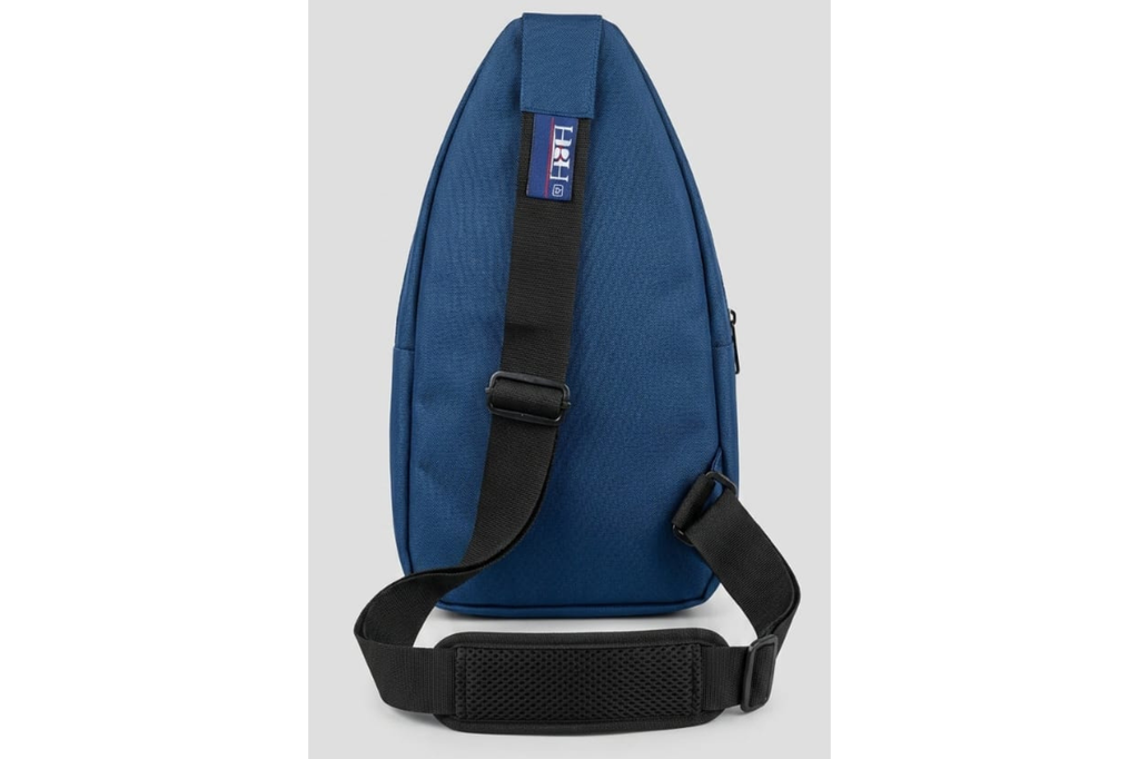 Blue sling bag with black strap on a light gray background